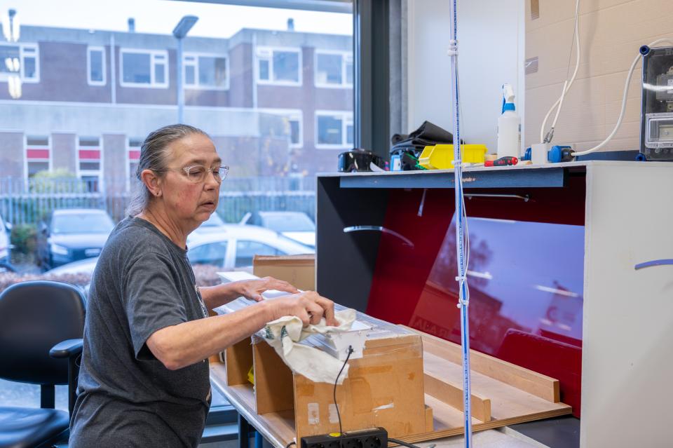 Medewerker maakt een lichtarmatuur schoon met een doek