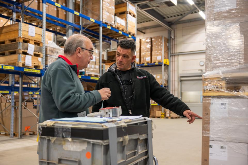 Twee magazijnmedewerkers bekijken een stapel dozen